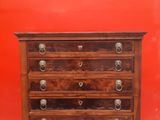 a wooden chest of drawers against a red wall