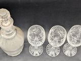 four glasses and a decanter sitting next to each other