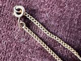 purple sweater with a chain and a silver ball on it
