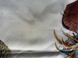 a white shirt with a picture of a bird and feathers on it