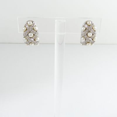 a pair of pearl and diamond earrings on a clear stand