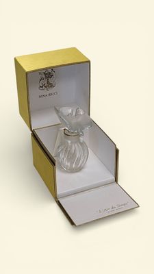 a glass perfume bottle in a box on a white surface