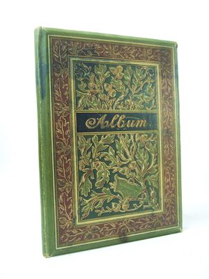 an old book with a gold and green cover on a white background
