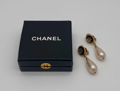 a pair of chanel earrings and a box on a table