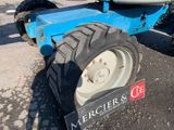 a blue tractor that is parked on the street
