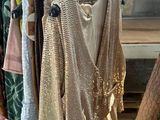 clothes hanging on a rack in a clothing store next to a wooden bench