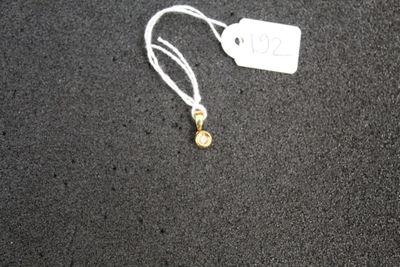 a white tag with a gold bead attached to it