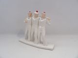 trois figurines de marins posées sur un socle blanc