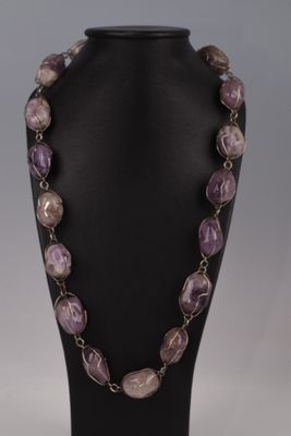 un collier composé de perles violettes et blanches, présenté sur un mannequin noir