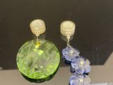 des boucles d'oreilles en cristal vert et bleu suspendues à un miroir dans une pièce