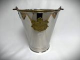 an antique silver ice bucket with a gold emblem on it