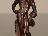 bronze statue of a man holding a bird on a tree stump