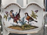two birds sitting on top of a bowl in a glass case