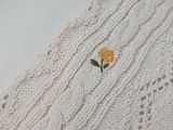 a white knitted scarf with yellow flowers on it