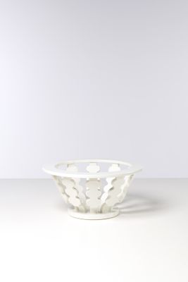 un bol blanc posé sur une table près d'un mur blanc
