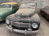 two old cars parked in a garage with graffiti on the walls