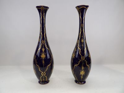 une paire de vases noirs et dorés posés sur une surface blanche