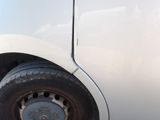 a small white car with a flat tire on the road