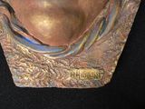 a bronze sculpture of a woman ' s face on a black surface