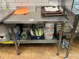 une table de travail en acier inoxydable sur laquelle sont posés tout un tas de plats