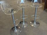 three clear stools sitting on top of a floor next to each other