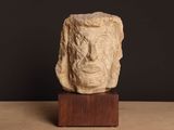 sculpture représentant le visage d'un homme, posée sur un socle en bois