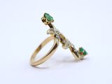 a close up of a gold ring with green stones