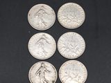 six different types of silver coins on a black surface