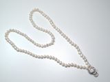 a white pearl necklace with a silver clasp on a white table
