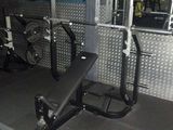 une salle de sport équipée d'un banc, d'haltères et d'une poubelle