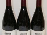 trois bouteilles de vin sont alignées sur une table