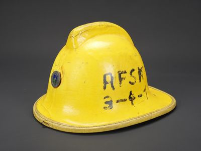 un vieux casque de chantier jaune avec une inscription sur le côté