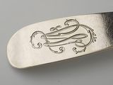 a silver spoon with a monogram on it sitting on a table