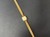 une montre en or posée sur une surface noire, avec un bracelet en or