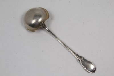 cuillère en argent dont le manche repose sur une surface blanche