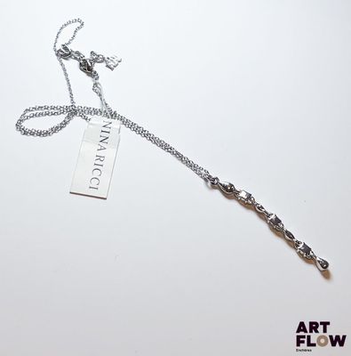 une chaîne en argent avec un pendentif, posée sur une surface blanche
