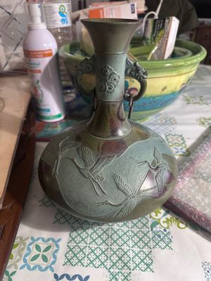 a green vase sitting on a table next to a bowl