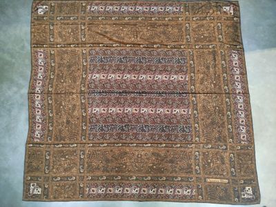 Le tapis posé au sol est marron et comporte un motif.