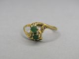 gros plan d'une bague en or avec une pierre verte