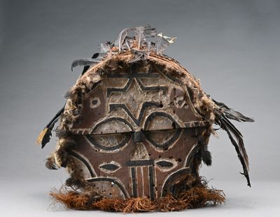 une image représentant un masque en bois orné de plumes