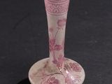 a small pink vase sitting on a black surface