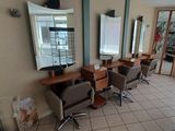 une photo d'un salon de coiffure avec des fauteuils et des miroirs