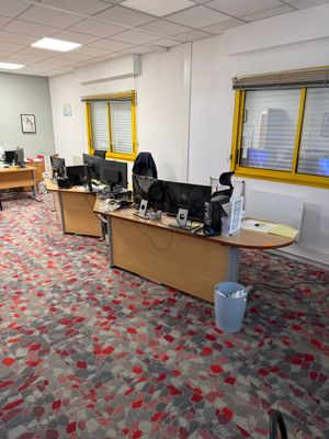 un tapis aux couleurs vives dans un bureau équipé de deux bureaux et de deux ordinateurs