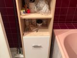 a small cabinet in the corner of a bathroom with a pink bathtub