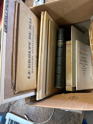 de nombreux livres dans une boîte posée sur une table, à côté d'un ordinateur portable