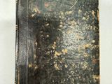 un vieux livre à la couverture noire posé sur une table