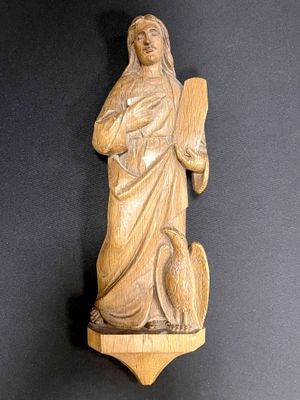 une statue en bois représentant une femme tenant un oiseau, posée sur une table