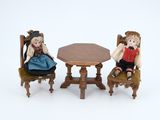 two dolls that are sitting at a table and chairs