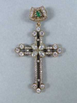 un gros plan d'une croix ornée d'une pierre verte
