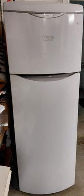un réfrigérateur blanc posé dans un garage à côté d'autres appareils électroménagers